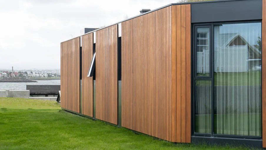 Einbýlishús á Íslandi klætt Western Red Cedar í lóðréttri lögn, með sjóinn í baksýn